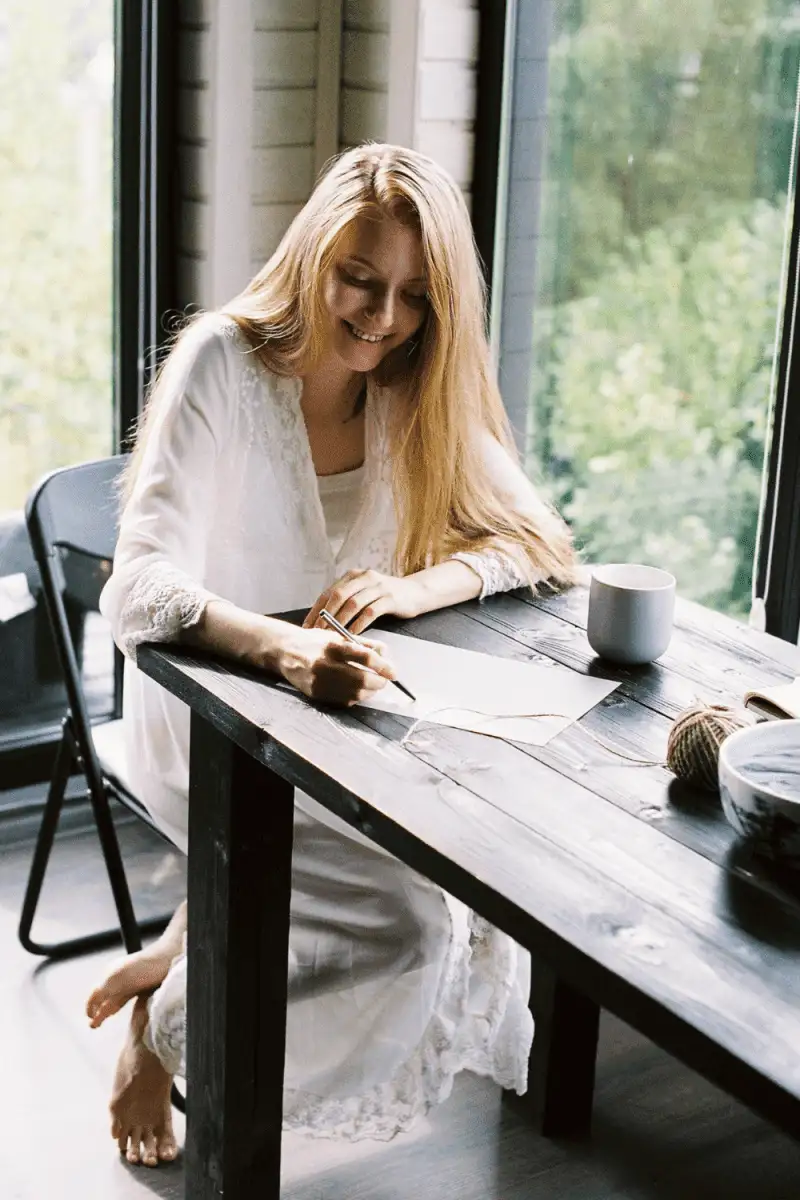 A girl writing love letters for him while sitting on the table