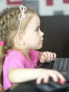 a little girl sitting in front of a computer keyboard