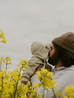 a man and woman kissing in a field of yellow flowers