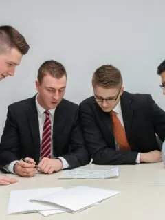 four men looking to the paper on table
