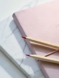 red and purple coloring pencils on pink journal