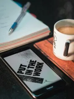 Honor smartphone beside mug and paper with pen