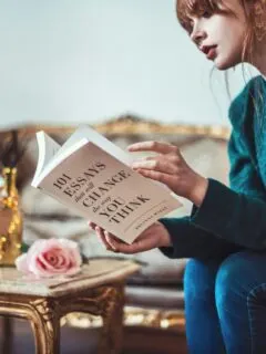 woman sitting down near table reading 101 Essays book