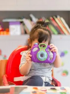 girl holding purple and green camera toy