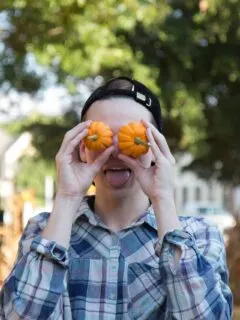 person wearing blue button-up dress shirt holding a two orange squashes